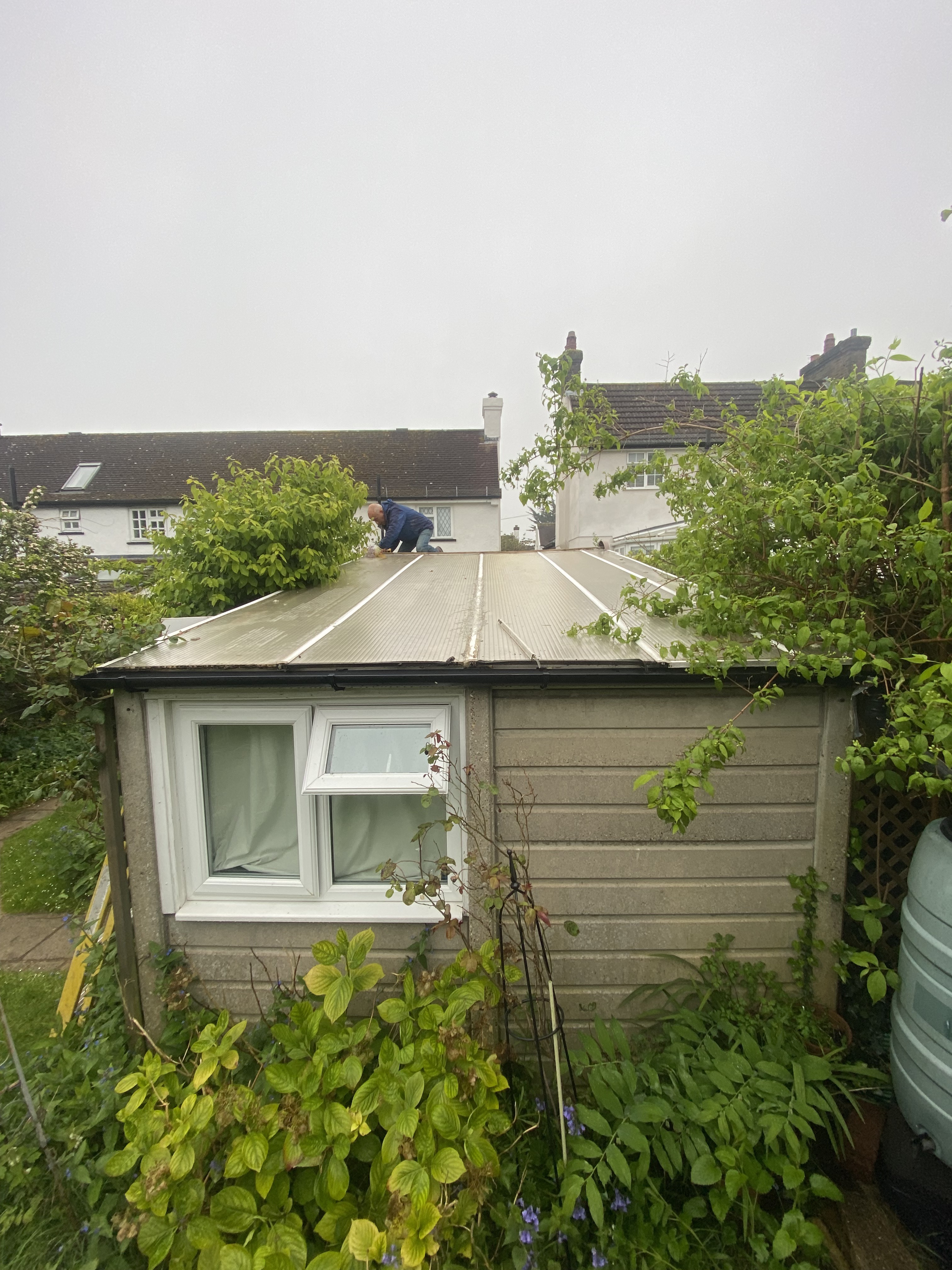 Operative in full PPE safely removing an asbestos garage roof