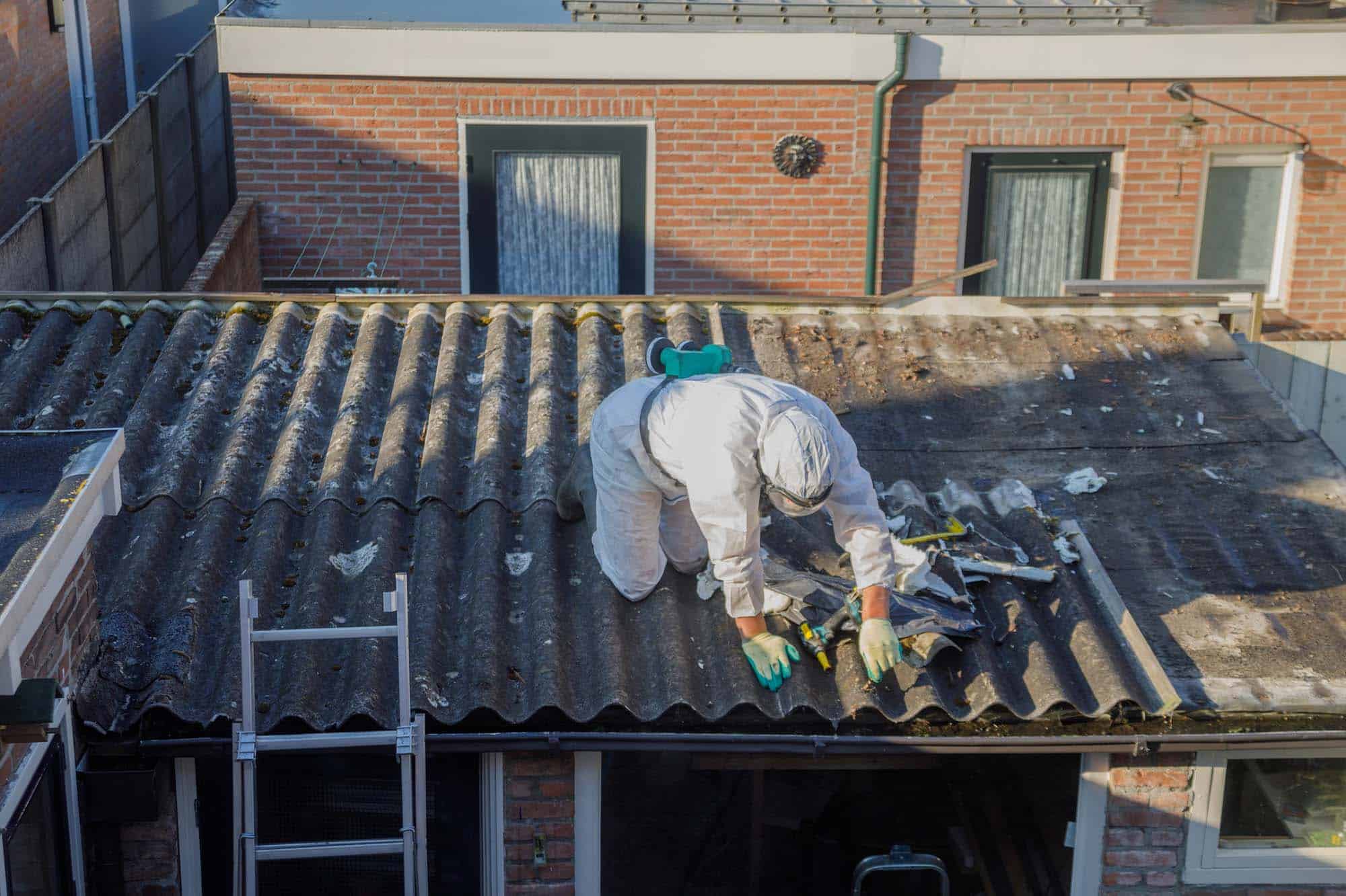 Professional asbestos removal. Men in protective suits are removing asbestos cement corrugated roofing