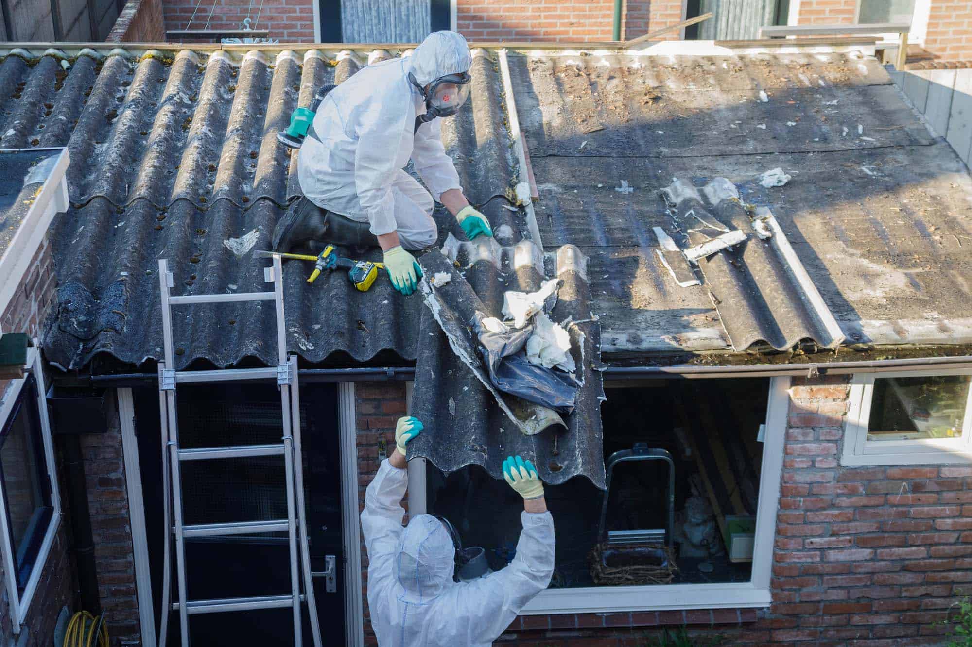 Professional asbestos removal. Men in protective suits are removing asbestos cement corrugated roofing