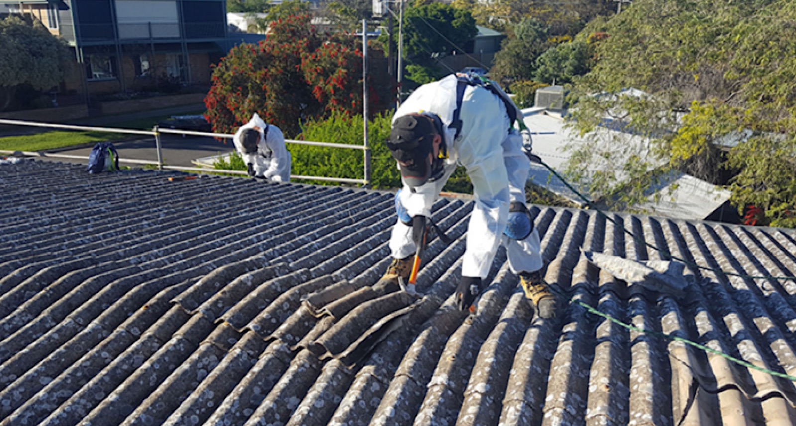 Operative in full PPE safely removing an asbestos garage roof